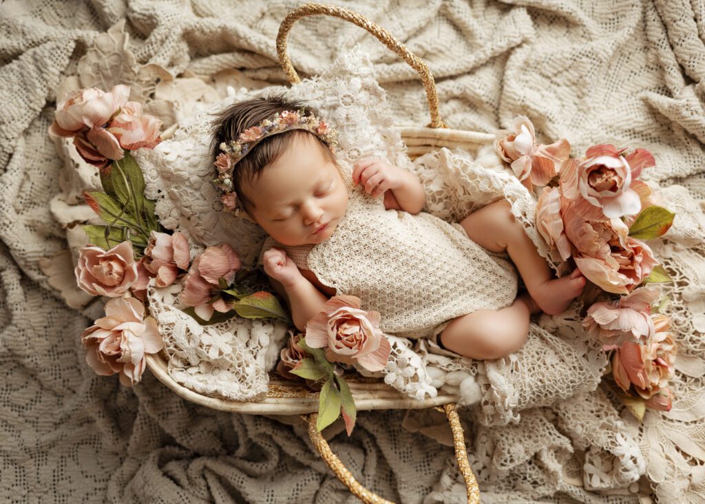 Sleeping newborn baby laying in a basket with flowers. Connecticut best Infant & Newborn Photographer Serving all of CT and Westchester County NY